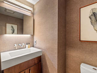 This powder room features a modern white vessel sink atop a dark wood vanity, complemented by sleek chrome fixtures.