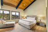 Experience luxury mountain living in this stunning bedroom, featuring a spacious king-sized bed and a comfortable chaise lounge.