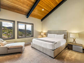 Experience luxury mountain living in this stunning bedroom, featuring a spacious king-sized bed and a comfortable chaise lounge.