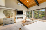 Experience luxury mountain living in this stunning bedroom featuring a modern gas fireplace and a large flat-screen TV.