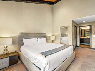 Experience luxury in this master bedroom featuring a king-sized bed with crisp white linens and a plush upholstered headboard.