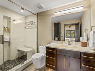 Experience modern luxury in this stunning bathroom, featuring a spacious walk-in shower with elegant tile work and a built-in bench.