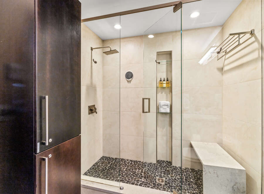 Experience luxury in this modern bathroom featuring a spacious walk-in shower with a rainfall showerhead and a built-in bench.