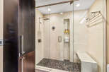 Experience luxury in this modern bathroom featuring a spacious walk-in shower with a rainfall showerhead and a built-in bench.