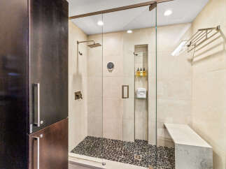 Experience luxury in this modern bathroom featuring a spacious walk-in shower with a rainfall showerhead and a built-in bench.