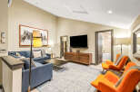 Experience modern comfort in this stylish living room, featuring a deep blue sectional sofa complemented by vibrant orange accent chairs.