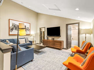 Experience modern comfort in this stylish living room, featuring a deep blue sectional sofa complemented by vibrant orange accent chairs.