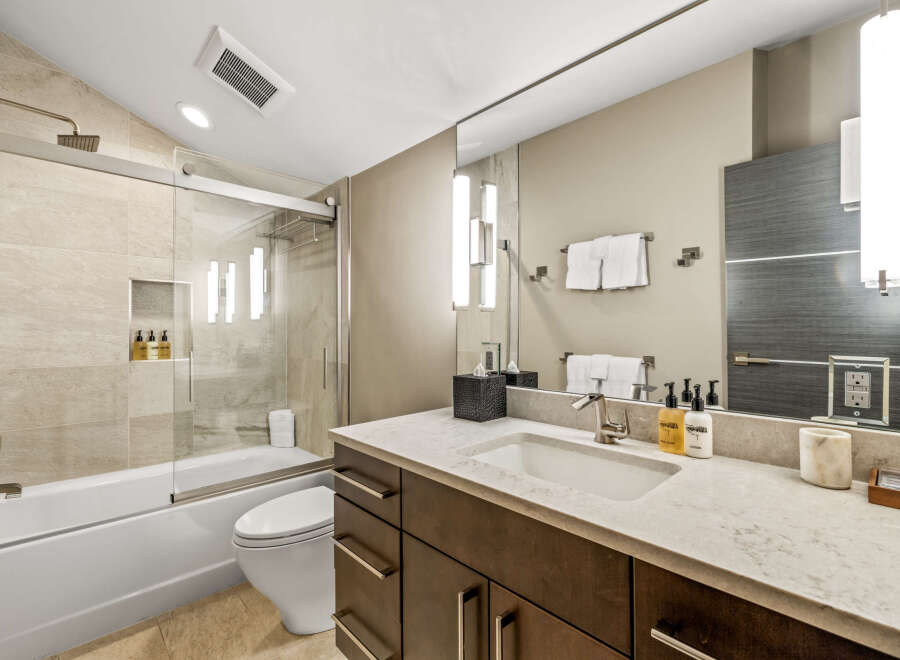 Experience modern luxury in this beautifully appointed bathroom, featuring a sleek bathtub and shower combination with elegant tilework.