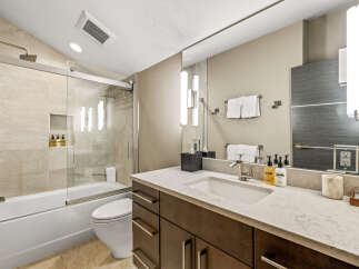 Experience modern luxury in this beautifully appointed bathroom, featuring a sleek bathtub and shower combination with elegant tilework.