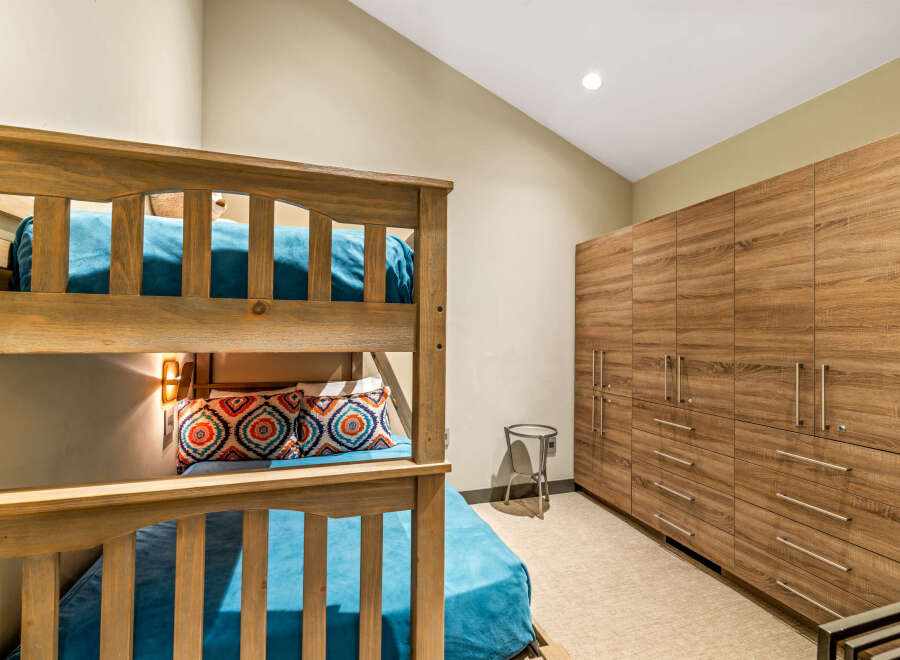 This bedroom features a charming wooden bunk bed with vibrant teal bedding and decorative pillows, perfect for accommodating guests.