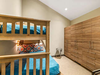 This bedroom features a charming wooden bunk bed with vibrant teal bedding and decorative pillows, perfect for accommodating guests.