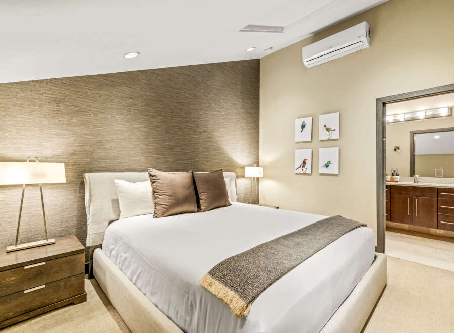 Experience modern comfort in this beautifully appointed bedroom, featuring a king-sized bed with plush pillows and a textured accent wall.