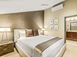 Experience modern comfort in this beautifully appointed bedroom, featuring a king-sized bed with plush pillows and a textured accent wall.