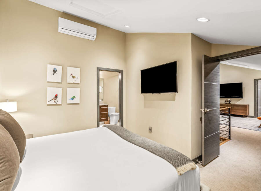 This bedroom offers a comfortable and modern retreat, featuring a plush bed adorned with decorative pillows and a cozy throw.