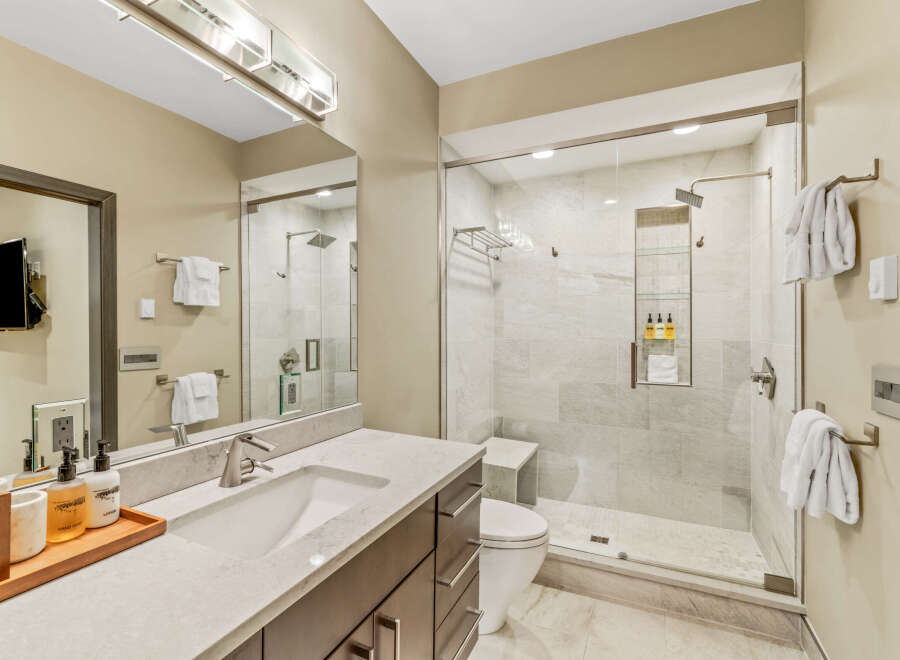 Experience modern luxury in this stunning bathroom featuring a spacious walk-in shower with elegant tile work and a built-in bench.