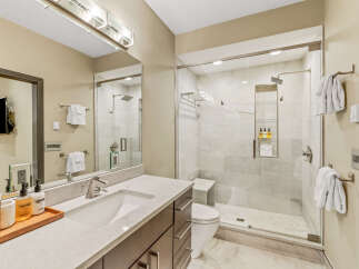 Experience modern luxury in this stunning bathroom featuring a spacious walk-in shower with elegant tile work and a built-in bench.