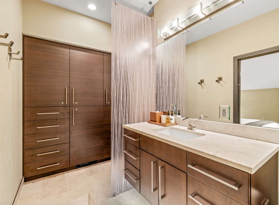 This modern bathroom features a sleek vanity with a stone countertop and a undermount sink, complemented by dark wood cabinetry.