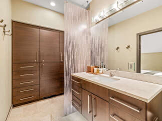 This modern bathroom features a sleek vanity with a stone countertop and a undermount sink, complemented by dark wood cabinetry.