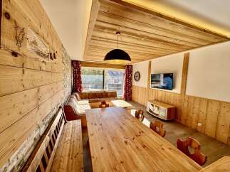Experience cozy living in this charming mountain retreat, featuring a spacious dining area with a rustic wooden table and benches, perfect for family gatherings.