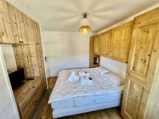 Experience rustic charm in this cozy bedroom featuring a comfortable bed adorned with fresh white linens and plush towels.