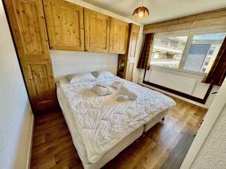 Experience cozy mountain living in this charming bedroom featuring a comfortable bed adorned with plush white linens and fluffy towels.
