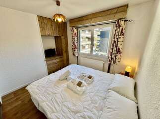 Experience cozy mountain living in this charming bedroom, featuring a comfortable bed adorned with plush white robes and towels, ready for relaxation.