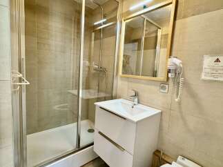 This modern bathroom features a sleek shower enclosure with chrome fixtures, a floating vanity with ample storage, and a clean-lined toilet.