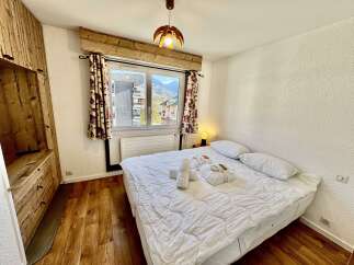 Experience cozy mountain living in this charming bedroom featuring a comfortable bed adorned with plush white linens and fluffy towels.