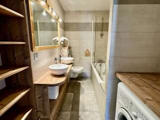 Discover this charming bathroom featuring a double vanity with vessel sinks, a modern toilet, and a bathtub with a shower.