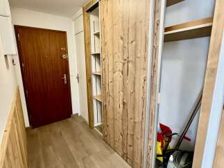 Discover this charming entryway featuring a rich wooden door and a spacious sliding door wardrobe with a natural wood finish.