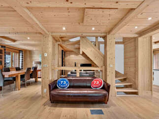 Experience rustic charm in this beautifully appointed wooden chalet, featuring a spacious dining area with a large wooden table and comfortable seating.