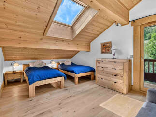 Experience alpine charm in this cozy attic bedroom, featuring two twin beds with vibrant blue bedding and playful sheep pillows.
