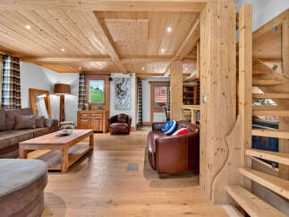 Experience rustic charm in this beautifully appointed living room, featuring a warm wooden ceiling and floors that create a cozy alpine ambiance.
