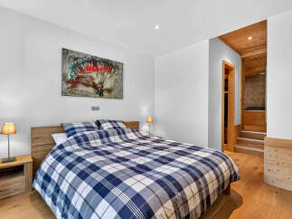 Experience ultimate comfort in this beautifully appointed bedroom, featuring a plush king-size bed dressed in a stylish blue and white plaid comforter.