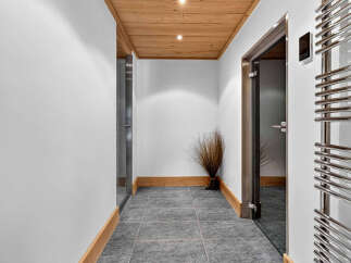 Experience modern comfort in this hallway featuring a sleek chrome towel warmer and a stylish wooden ceiling.