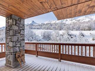 Experience the ultimate winter wonderland from this charming balcony, complete with a rustic stone pillar and a pair of snowshoes ready for adventure.