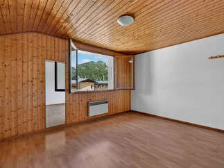 Experience breathtaking mountain views from this charming room featuring warm wooden paneling and a spacious window.
