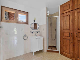 Discover this charming bathroom featuring a spacious wooden cabinet, a modern vanity with a sink, and a glass-enclosed shower.