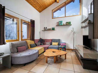 Experience cozy living in this charming mountain retreat, featuring a spacious sectional sofa perfect for gatherings and a unique, organic-shaped coffee table.