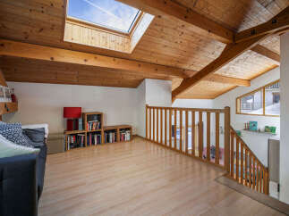 Experience cozy living in this charming attic space, featuring a beautiful wooden-beamed ceiling and a large skylight that floods the room with natural light.