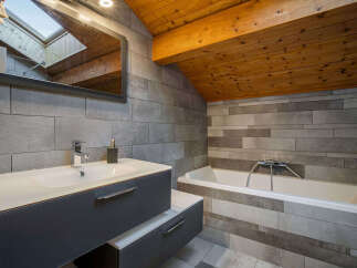 This modern bathroom features a sleek vanity with a white basin and a chrome faucet, complemented by a dark gray cabinet.