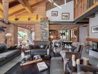 Experience luxurious alpine living in this stunning chalet, featuring a grand stone fireplace and exposed wooden beams.