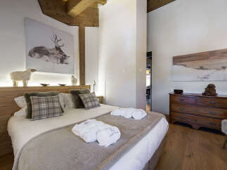 Experience rustic luxury in this charming bedroom, featuring a plush king-size bed adorned with cozy plaid pillows and soft throws.