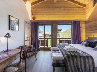 Experience luxury mountain living in this stunning chalet bedroom, featuring a cozy king-size bed adorned with plush throws and elegant plaid accents.