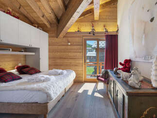 Experience cozy alpine living in this charming bedroom, featuring a plush bed adorned with plaid pillows and soft robes.