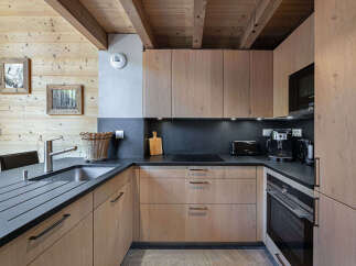 Experience modern alpine living in this beautifully appointed kitchen, featuring sleek wooden cabinetry and a durable dark countertop.