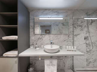 Experience modern luxury in this beautifully appointed bathroom, featuring a sleek vanity with a vessel sink and marble-patterned walls.