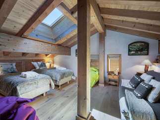 Experience rustic charm in this attic bedroom featuring two cozy twin beds with plush bedding and decorative pillows.