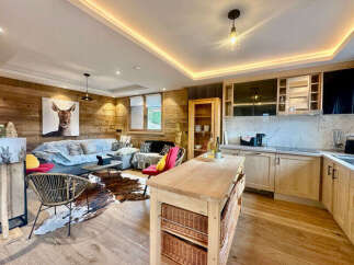 Experience modern alpine living in this stunning open-plan space, featuring a cozy living area with a striking deer artwork and a fully equipped kitchen with sleek cabinetry.