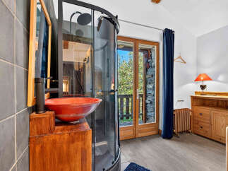 Experience rustic charm and modern convenience in this unique bathroom featuring a striking red vessel sink and a sleek glass shower enclosure.